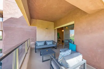 a balcony with a couch and tables on a building at Modern Appart-Golf View, Terrace & Fiber Optic in Marrakech