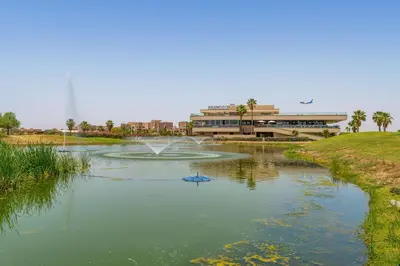 a pond in a park with a building and a fountain at Modern Appart-Golf View, Terrace & Fiber Optic in Marrakech