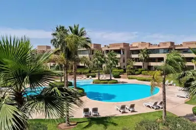 a resort with a large swimming pool and palm trees at apartment sur GOLF prestigia avec piscine in Marrakech