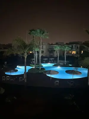 a large pool with palm trees and umbrellas at night at apartment sur GOLF prestigia avec piscine in Marrakech