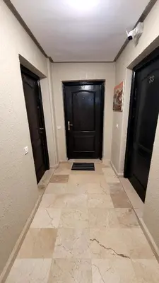 a hallway with two black doors and a tile floor at Le Chaleureux 34 face de la gare CTM Hivernage in Marrakech