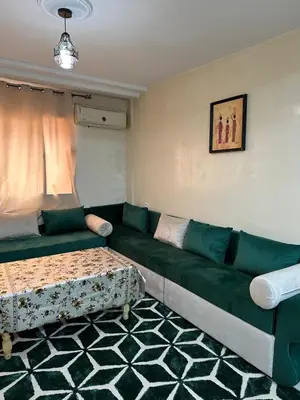 a living room with a green couch and a table at Le Chaleureux 34 face de la gare CTM Hivernage in Marrakech