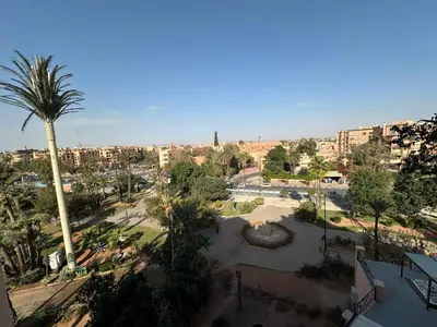 a view of a park with a palm tree and buildings at Duplex à l hivernage in Marrakech