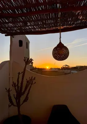 a pendant light and a cactus in front of a sunset at Riad Le Jardin des Matières in Marrakech