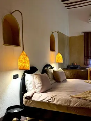 a bedroom with a bed with two lamps on the wall at Riad Le Jardin des Matières in Marrakech