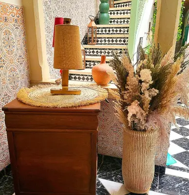 a table with a lamp and a vase with flowers on it at Riad Marhaba Marrakech in Marrakech