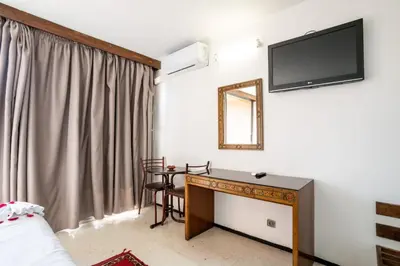 a room with a desk and a television on the wall at Hotel Le Grand Imilchil in Marrakech