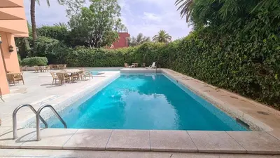 a swimming pool with a table and chairs next to a building at Hotel Le Grand Imilchil in Marrakech