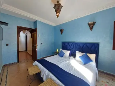 a bedroom with a large bed with blue walls at Jasmin d'Atlas in Marrakech