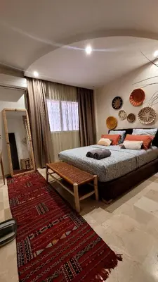 a bedroom with a large bed and a rug at le chaleureux a 10mn de l'aeroport face a la gare CTM Hivernage in Marrakech