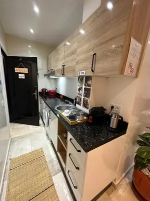 a small kitchen with a black counter top and wooden cabinets at le chaleureux a 10mn de l'aeroport face a la gare CTM Hivernage in Marrakech