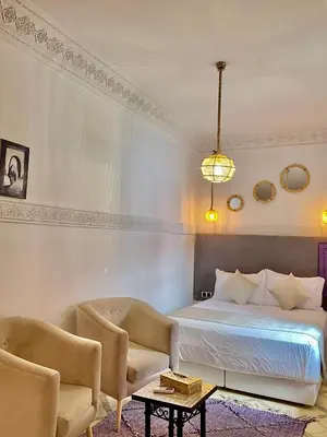 a bedroom with a bed and two chairs and a table at Riad Al Wafaa in Marrakech