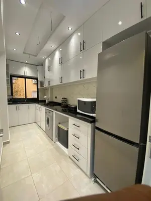 a large kitchen with white cabinets and a refrigerator at Appartement Idéal pour Votre Séjour in Marrakech
