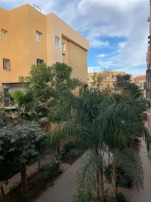 a building with palm trees in front of it at Appartement Idéal pour Votre Séjour in Marrakech