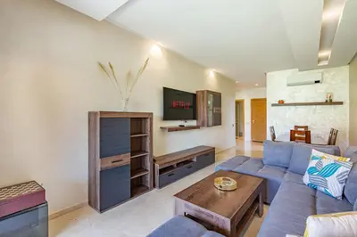 a living room with a blue couch and a tv at Luxury Garden-Level Apartment with Poolside Serenity in Marrakech