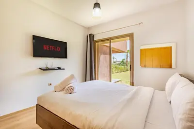 a bedroom with a bed and a tv on the wall at Luxury Garden-Level Apartment with Poolside Serenity in Marrakech