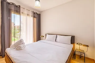 a bedroom with a large white bed and a window at Luxury Garden-Level Apartment with Poolside Serenity in Marrakech