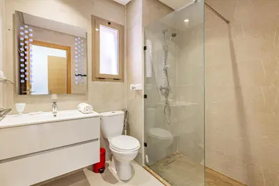 a bathroom with a toilet and a glass shower at Luxury Garden-Level Apartment with Poolside Serenity in Marrakech