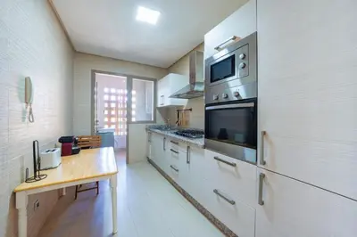 a kitchen with white cabinets and a wooden table at Apart Confort Rez-de-Jardin Piscine Wi-Fi Terrasse in Marrakech