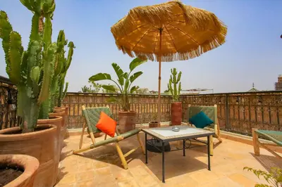 a patio with chairs and a table and an umbrella at Riad Tampacao in Marrakech