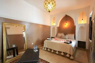 a bedroom with a large bed and a mirror at Riad Tampacao in Marrakech