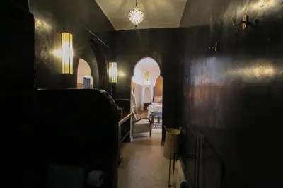 a hallway with black walls and a room with a table at Riad Tampacao in Marrakech
