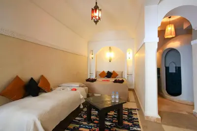 a hotel room with two beds and a table at Riad Tampacao in Marrakech