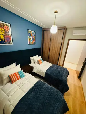 two beds in a room with blue walls at Luxury Apartment in Central Marrakech - Pool & Fast Wi-Fi in Marrakech