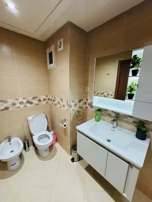 a bathroom with a toilet and a sink and a mirror at Luxury Apartment in Central Marrakech - Pool & Fast Wi-Fi in Marrakech