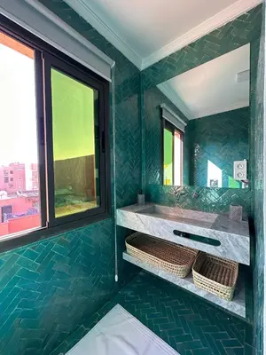 a green bathroom with a sink and a mirror at Apartment Gueliz Victor Hugo in Marrakech