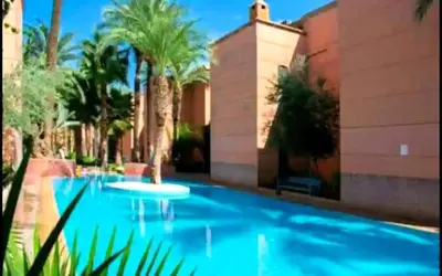 a blue swimming pool with palm trees and a building at MARRAKECh TYPICAL HOUSE MAISON TYPIQUE MARRAKECH G2 40 in Marrakech
