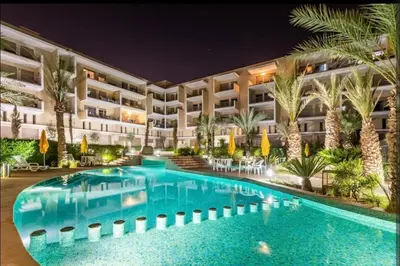 a hotel with a swimming pool at night at Bel appartement à Marrakech dans la résidence Pearl Garden avec piscine située sur la route de Casablanca Sa grande terrasse a une splendide vue sur la ville et les montagnes de l'Atlas A quelques minutes du centre ville et du grand Stade de Marrakech in Marrakech