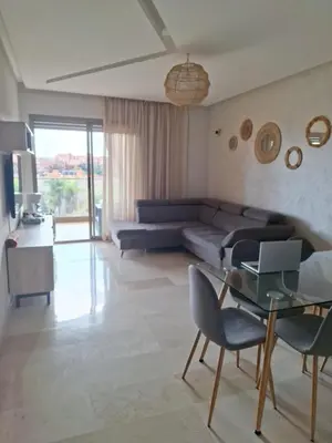a living room with a couch and a glass table at Bel appartement à Marrakech dans la résidence Pearl Garden avec piscine située sur la route de Casablanca Sa grande terrasse a une splendide vue sur la ville et les montagnes de l'Atlas A quelques minutes du centre ville et du grand Stade de Marrakech in Marrakech