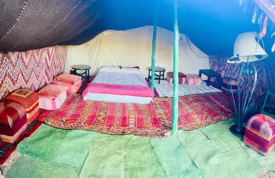 a bedroom with a bed and chairs in a tent at Tente berbère in Marrakech