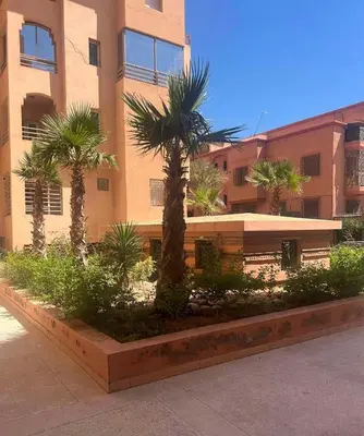 a building with palm trees in front of it at Calm & Cozy Studio with Balcony in Marrakech