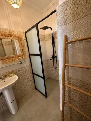 a bathroom with a shower with a sink and a mirror at A flat near the airport in Marrakech