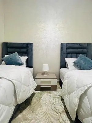 a bedroom with two beds and a table with a lamp at Bright downtown apartment in Marrakech