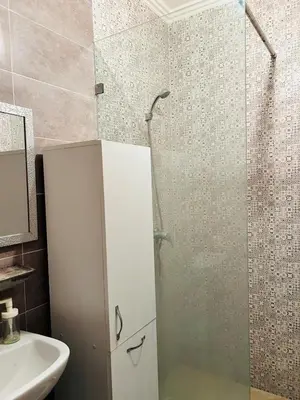a bathroom with a shower with a glass door at Bright downtown apartment in Marrakech
