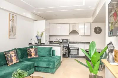 a living room with a green couch and a kitchen at Lux Oasis - Marrakech Center in Marrakech