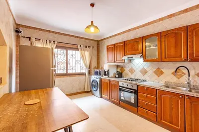 a kitchen with wooden cabinets and a table in it at New! Apt jacaranda, wifi and parking in Marrakech