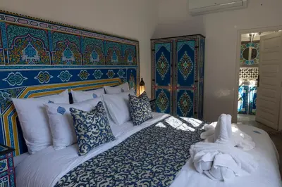 a bedroom with a large bed with blue and white pillows at Riad O'Zeen in Marrakech