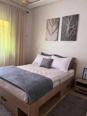 a large bed in a bedroom with two pictures on the wall at Appartement Marrakech 2 chambres Residence al Manar in Marrakech