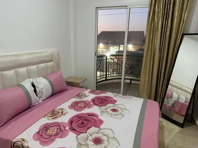 a bed with pink and white sheets and flowers on it at Le Chaleureux avec Balcon 8 face gare CTM Hivernage in Marrakech