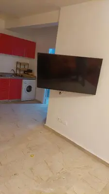 a kitchen with a tv hanging on a wall at Le Chaleureux avec Balcon 8 face gare CTM Hivernage in Marrakech