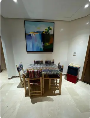 a dining room table with chairs and a painting on the wall at appartement à coté des palmeraies in Marrakech