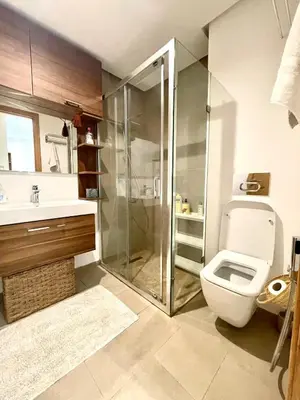 a bathroom with a toilet and a glass shower at Ana cosy - Clim, Wifi, Jardin à 10min de l'Aéroport in Marrakech