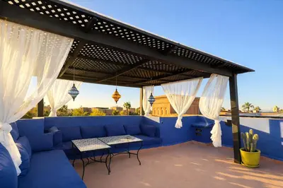 a patio with a blue couch and white curtains at Private Riad Alemania in Marrakesh - Pool - Rooftop in Marrakech
