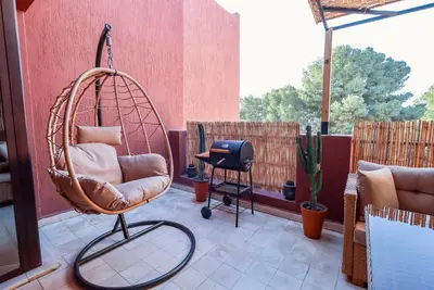 a swing chair sitting on a porch with a table at La Kasbah - 2bdr- Parking - Wifi - Terrasse in Marrakech
