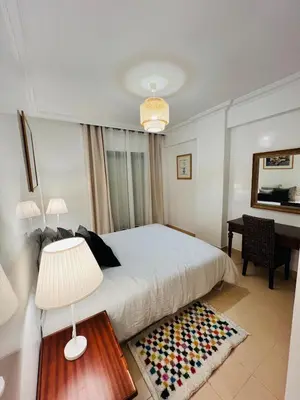 a bedroom with a bed with a lamp and a desk at Appartement Centre de Gueliz in Marrakech
