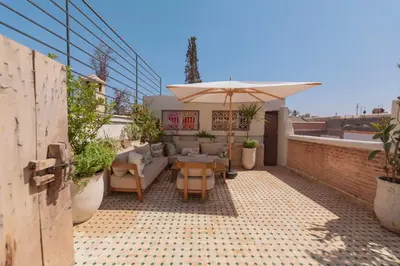 a patio with a table and an umbrella on a roof at Riad Dar Bousga in Marrakech
